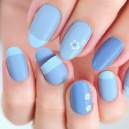 Nail set all nails are solid shades of light blue but each nail gets darker and darker as the nails go from the pink to the thumb. The middle finger on the left hand is light blue French tip and the middle finger on the right hand is several small doodle uwhite flowers. The nails are almond shaped but as short as possible like only a bit smaller than the length of natural nails.
