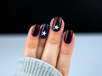 Dark maroon nails with navy blue ring finger with white star outline