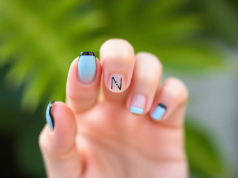 Almond shape 	•	pinky skin color base 	•	black micro French tips (very thin black line instead of thick tip)  	•	Ring finger: baby blue thin N letter in a bubble font  	•	Optional: tiny dot accents in baby blue near the cuticle