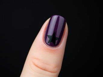 Extremely dark purple nails with a black star on the index finger