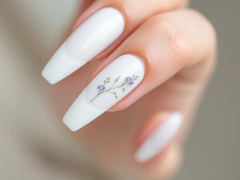 White long round acrylic nails. The ring finger is a white French tip with small delicate lavender and sage floral designs near the top edge of the nail